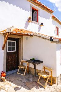 une table et deux chaises à l'extérieur d'une maison dans l'établissement Private, romantic and cozy Room in Azenhas do Mar, à Colares
