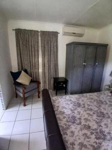 Un dormitorio con una cama, una silla y un sofá. en Karoo 2, en Douglas
