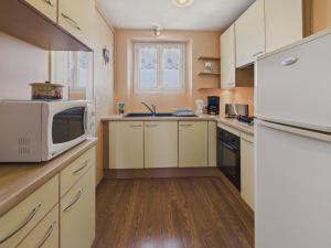 une cuisine avec des armoires blanches et un micro-ondes dans l'établissement Le port et les plages à pied pour 4 - Concarneau, à Concarneau