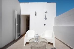 Zimmer mit zwei weißen Stühlen und einem Glastisch in der Unterkunft Penthouse 3A in Morro del Jable
