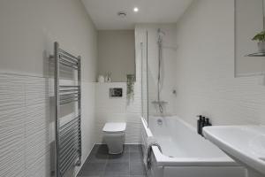 a bathroom with a tub and a toilet and a sink at Perfect for Silverstone Free Parking Stylish 2BR in Buckingham +23 photos