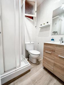 a white bathroom with a toilet and a shower at Coma-ruga central beach apartment in Comarruga