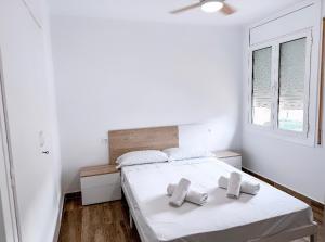 a white bedroom with a bed with two towels on it at Coma-ruga central beach apartment in Comarruga