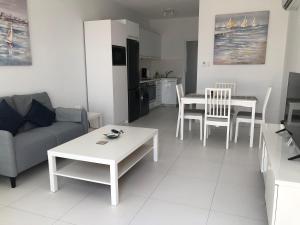 una sala de estar con un sofá y una mesa en Elegant beachside apt - 1 min walk to Venus beach, en Paphos