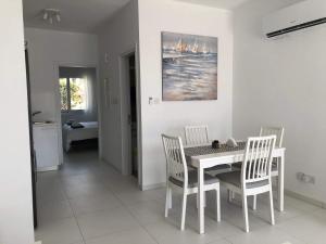 Un comedor blanco con una mesa y sillas. en Elegant beachside apt - 1 min walk to Venus beach, en Paphos