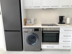 una cocina con lavadora y nevera en Elegant beachside apt - 1 min walk to Venus beach, en Paphos 19 fotos más