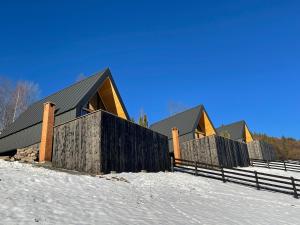 a house in the snow with a fence at Casa Boema- La noi la munte in Mătişeşti