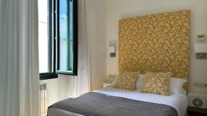 a bedroom with a bed with a headboard and a window at Hostal Casa Alborada in Conil de la Frontera