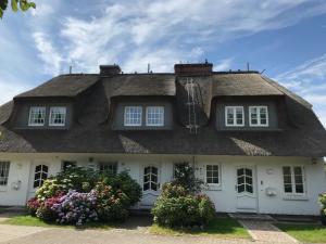 a thatched house with flowers in front of it at Hausteil Ruusenhoog in Braderup
