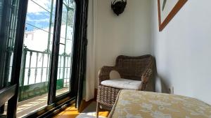 a wicker chair sitting in a room with a window at Hostal Casa Alborada in Conil de la Frontera