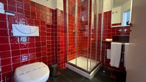 a red tiled bathroom with a toilet and a shower at Hostal Casa Alborada in Conil de la Frontera
