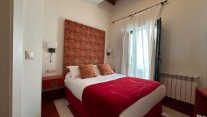 a bedroom with a bed with red sheets and a window at Hostal Casa Alborada in Conil de la Frontera