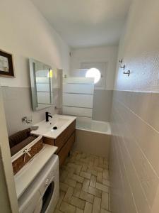 a bathroom with a sink and a tub and a mirror at Studio antigua in Le Grau-du-Roi