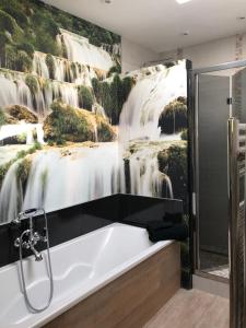 een badkuip in een badkamer met een watervalmuurschildering bij L'Hermione - Room in the heart of St Martin de Ré in Saint-Martin-de-Ré
