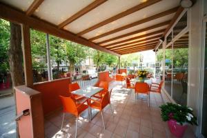 a covered patio with orange chairs and a table and chairs at Hotel Sport in Rimini