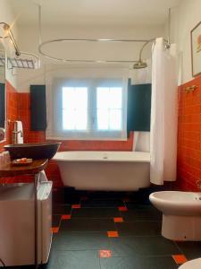 a bathroom with a tub and a toilet and a window at Hostal Casa Alborada in Conil de la Frontera