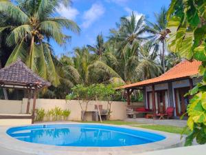a swimming pool in front of a house with palm trees at Tejakula Sunset Boutique Resort in Tejakula