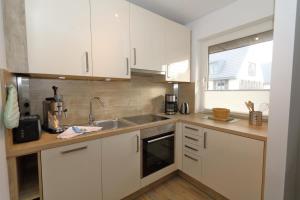 a kitchen with white cabinets and a sink at Entennest am Dorfteich in Wenningstedt +9 photos