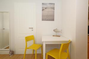 a room with a table and two yellow chairs at Haus sarah 08 in Westerland