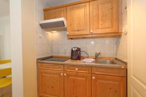 a small kitchen with wooden cabinets and a sink at Haus sarah 08 in Westerland
