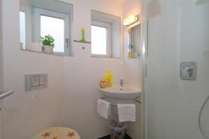 a white bathroom with a sink and a toilet at Haus sarah 08 in Westerland