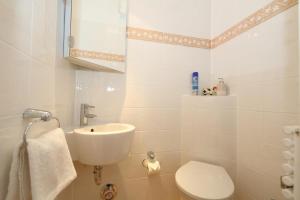 a white bathroom with a sink and a toilet at Sommer Munkmarsch in Munkmarsch +7 photos