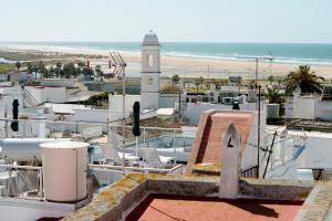a view of a town with a clock tower and the beach at Hostal Casa Alborada in Conil de la Frontera