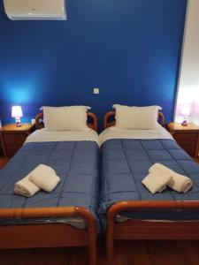two beds in a room with blue walls at Joel Apartment in Pefkali
