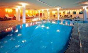 a pool in a hotel with tables and chairs at Hotel Zinnkrügl in Sankt Johann im Pongau