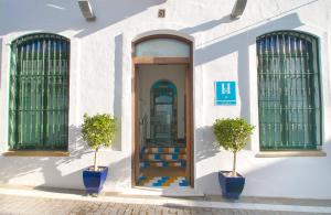 a white building with a door and two potted plants at Hostal Casa Alborada in Conil de la Frontera