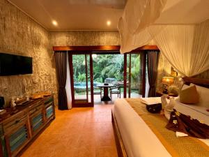 a bedroom with a bed and a television and a table at Royal Amertha Ubud Jungle View in Gianyar