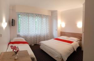 a hotel room with two beds and a window at Les nouveaux Ambassadeurs in Saint-Chamond