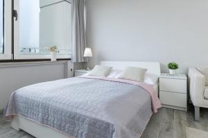 a white bedroom with a bed and a window at Marina Wendtorf Kajüte in Wendtorf