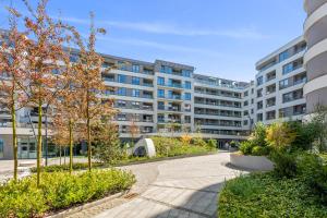グディニャにあるPlac Unii Gdynia Central by Lion Apartmentsの木々や茂みのある中庭のあるアパートメントビル