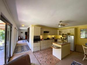 une grande cuisine avec des murs jaunes et des armoires blanches dans l'établissement Jennys Farm Cottage, à Robertson