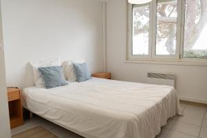 un letto bianco con cuscini blu in una camera da letto di Villa Bertaud les pieds dans l'eau a Andernos-les-Bains