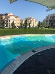 a large blue swimming pool with buildings in the background at Тристаен апартамент в затворен комплекс in Chernomorets