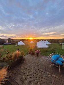 a sunset over a deck with tents in a field at The Paddock Wildcamp in Perranporth