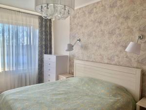 Un dormitorio con una cama y una lámpara de araña. en Forest gateway, en Jūrmala