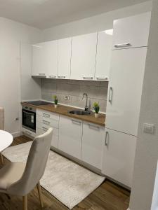 cocina con armarios blancos, fregadero y silla en Villa House Ilda, en Bar