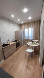 a kitchen with a table and a table and a table and chairs at Посуточно 1 комнатная Драмтеатр, ЖК Park city, Green Leaf, Noviy Bereg, ТЦ MAXI MALL in Ustʼ-Kamenogorsk