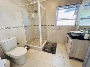 a bathroom with a shower and a toilet and a sink at Rissie's Place in Gordonʼs Bay +5 photos