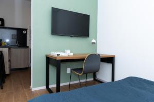 a desk with a chair and a television on a wall at Guaja 745 - Apartamento Luna in Belo Horizonte