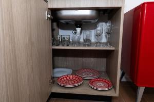 a cupboard with red plates and wine glasses at Guaja 745 - Apartamento Luna in Belo Horizonte