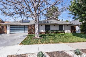ein Haus mit einem Baum vor einer Einfahrt in der Unterkunft Luxury 3BR with Cabana Oasis Pool & Style in Costa Mesa