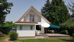 a small white house with a balcony and an umbrella at Residence at lake Balaton in Siófok