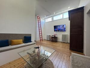 a living room with a couch and a tv on a wall at Le Saint Victeur - 8pers - Babyfoot - Rêve au Mans in Le Mans