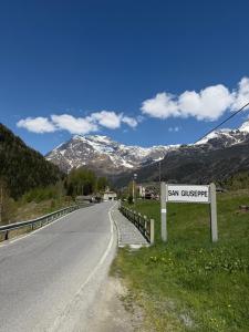 a sign on the side of a road with mountains at Sabbionaccio Apartments & Spa in Chiesa in Valmalenco