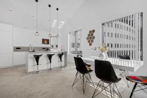 a white kitchen with black chairs and a white table at Reykjavik Luxury Hotel Apartments KARTULI in Reykjavík