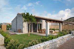 a stone house with a patio and a stone wall at Villa Granito in Castiadas